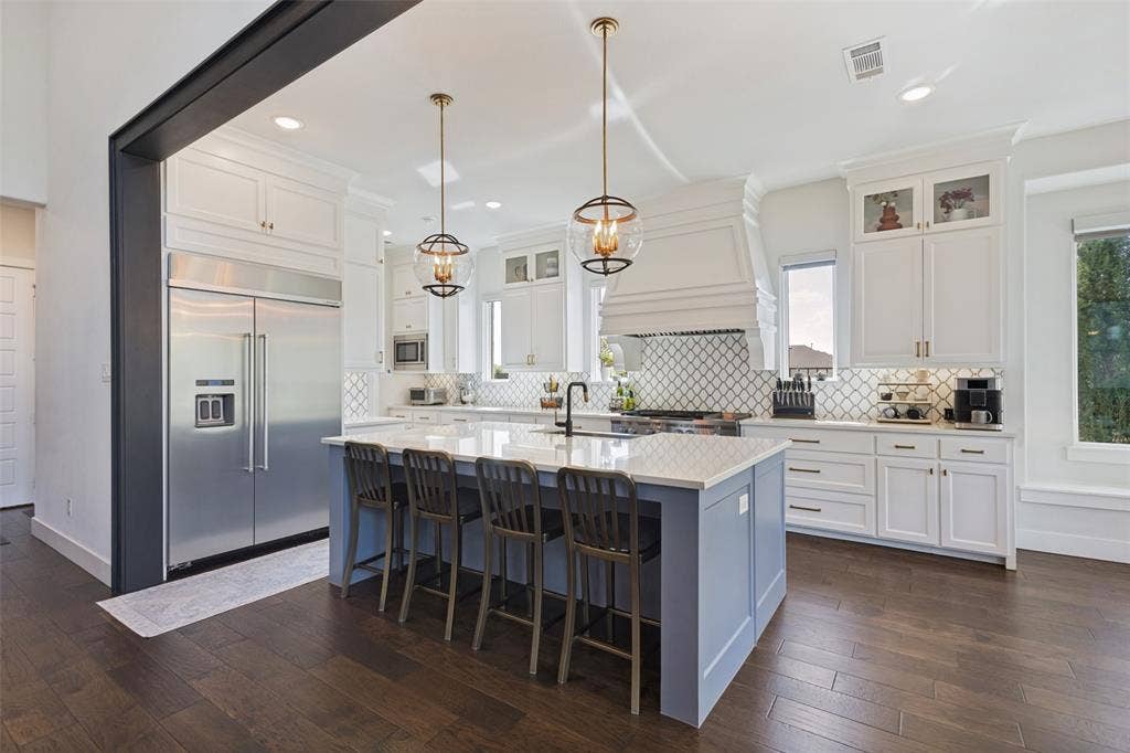 15018 Crape Myrtle Road, Frisco, TX 75035 Kitchen featuring wood-finish flooring, white cabinetry, integrated stainless steel refrigerator, kitchen island with seating, and decorative pendant lighting