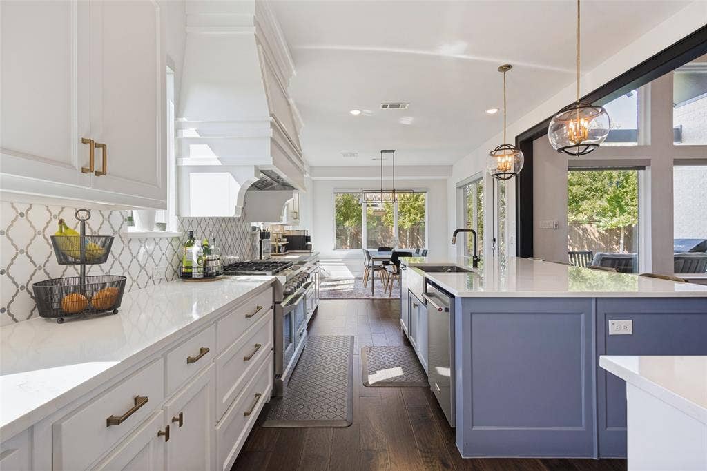 15018 Crape Myrtle Road, Frisco, TX 75035 Gourmet kitchen with white perimeter cabinetry, a large range, a custom range hood, a contrasting blue island, and wood-finish flooring