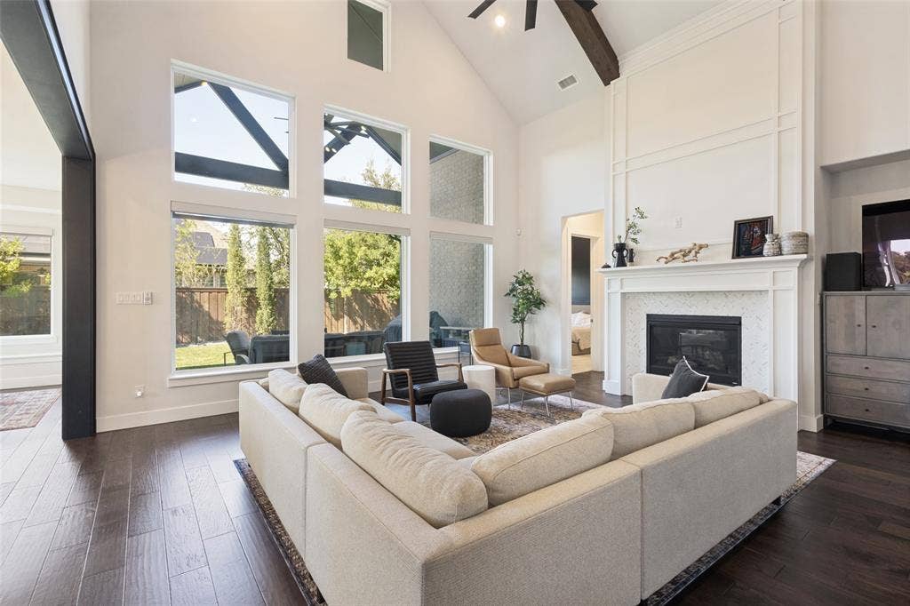 15018 Crape Myrtle Road, Frisco, TX 75035 Vaulted ceilings with exposed wood beam, dark wood-finish flooring, and a fireplace with a white mantel and tile surround