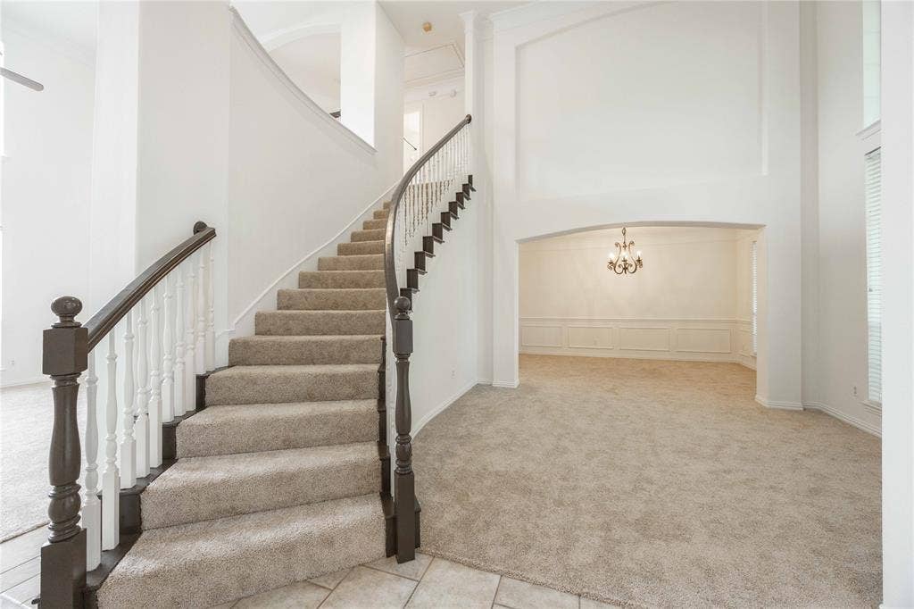 3305 Estacado Lane, Plano, TX 75025 Curved staircase with wood newel posts and balusters, carpeted treads, and tiled entry