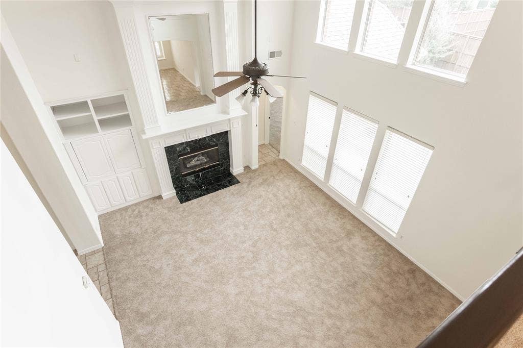 3305 Estacado Lane, Plano, TX 75025 Two-story living area featuring a ceiling fan, fireplace with dark stone surround, white mantel, and built-in white cabinetry