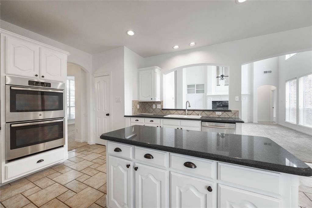 3305 Estacado Lane, Plano, TX 75025 Kitchen featuring white cabinetry, stainless steel double ovens, a center island with a dark countertop, and tiled flooring