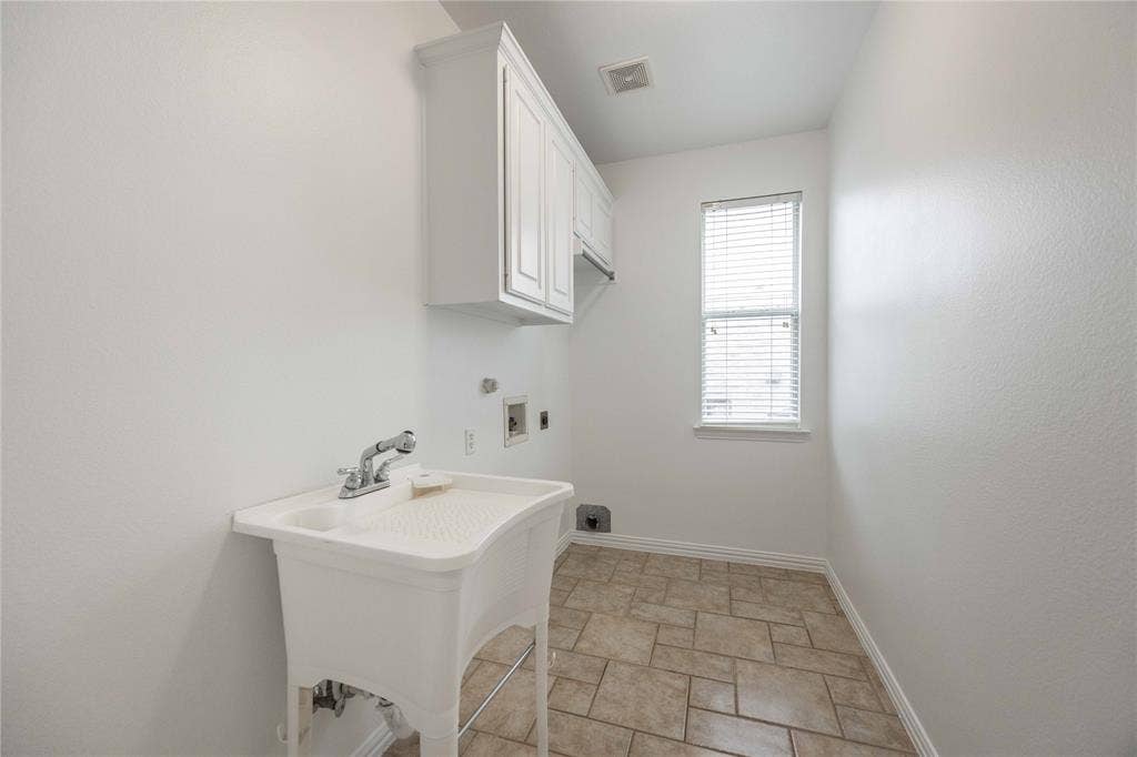 3305 Estacado Lane, Plano, TX 75025 Utility sink, upper cabinetry, window with blinds, and tile flooring