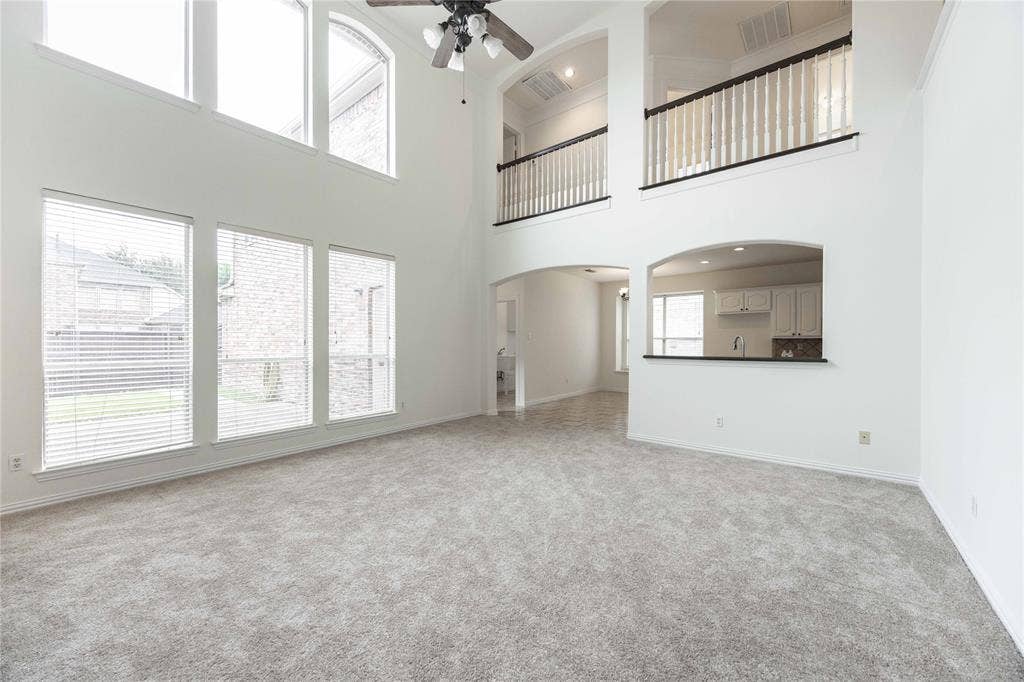 3305 Estacado Lane, Plano, TX 75025 Two-story living area with high ceilings, upper-level windows, and an arched pass-through to the kitchen