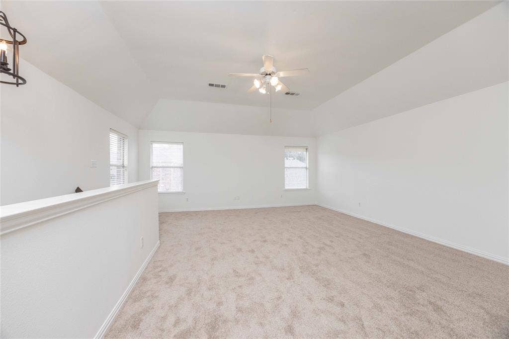 3305 Estacado Lane, Plano, TX 75025 Spacious room featuring vaulted ceilings, neutral carpeting, two windows, and a ceiling fan