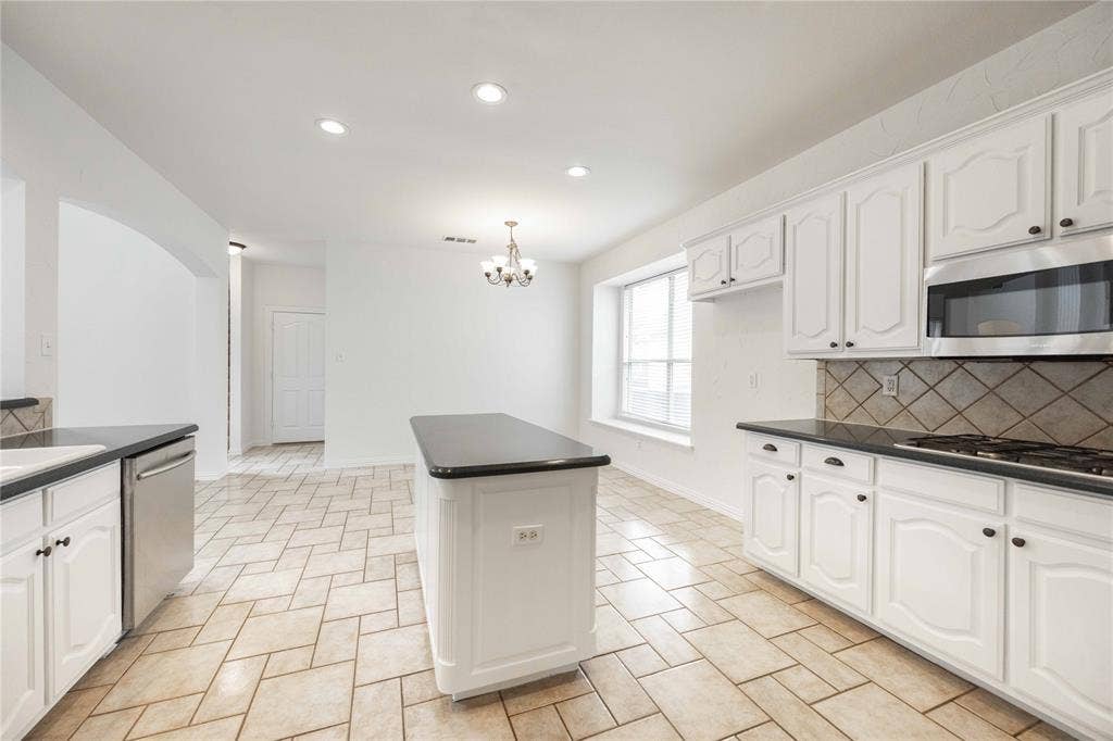 3305 Estacado Lane, Plano, TX 75025 Kitchen featuring white cabinetry, dark countertops, a tile backsplash, stainless steel appliances, and a central island