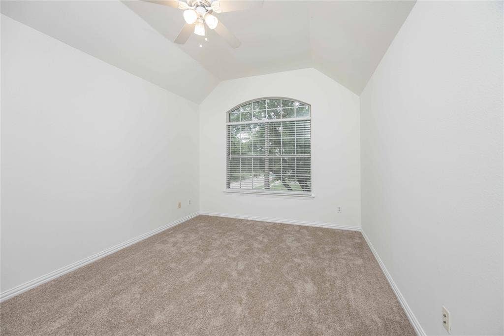 3305 Estacado Lane, Plano, TX 75025 Vaulted ceiling with an installed ceiling fan, an arched window, and carpet flooring