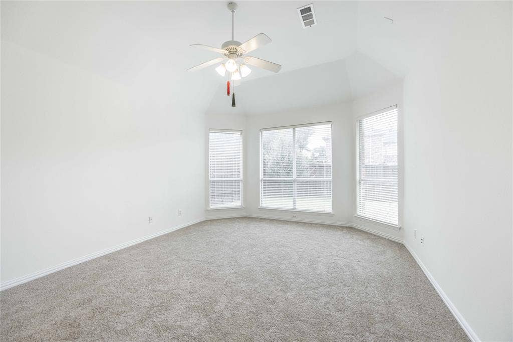 3305 Estacado Lane, Plano, TX 75025 Vaulted ceiling with a ceiling fan, bay window configuration, multiple windows with blinds, and light-toned carpeting