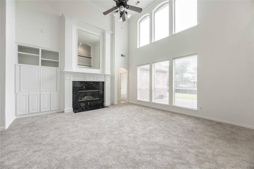 3305 Estacado Lane, Plano, TX 75025 Two-story living area with high ceilings, a built-in media cabinet, a fireplace with a dark stone surround, and multiple windows