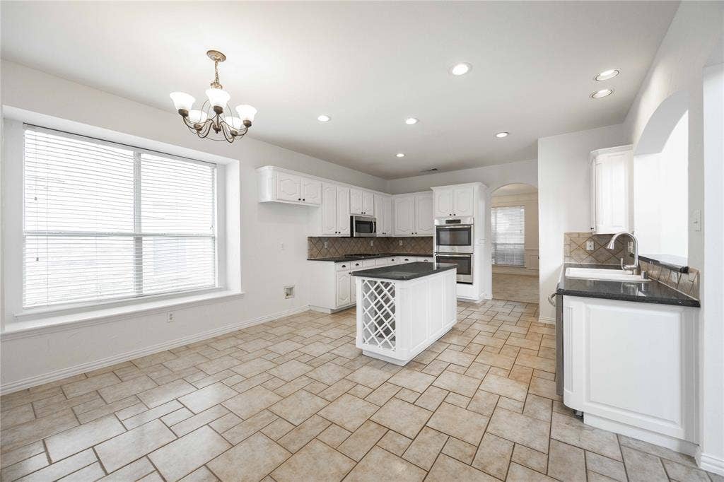 3305 Estacado Lane, Plano, TX 75025 Kitchen featuring white cabinetry, dark countertops, a central island with wine storage, recessed lighting, and a chandelier