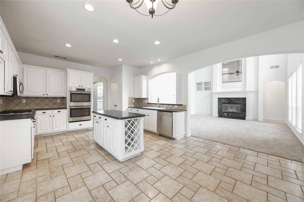 3305 Estacado Lane, Plano, TX 75025 Kitchen featuring white cabinetry, dark countertops, a double wall oven, a center island with built-in wine storage, and tile flooring