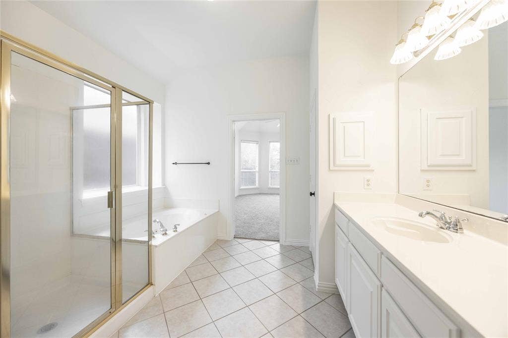 3305 Estacado Lane, Plano, TX 75025 White tiled flooring, vanity with a single basin, built-in storage above the vanity, separate shower, and built-in bathtub