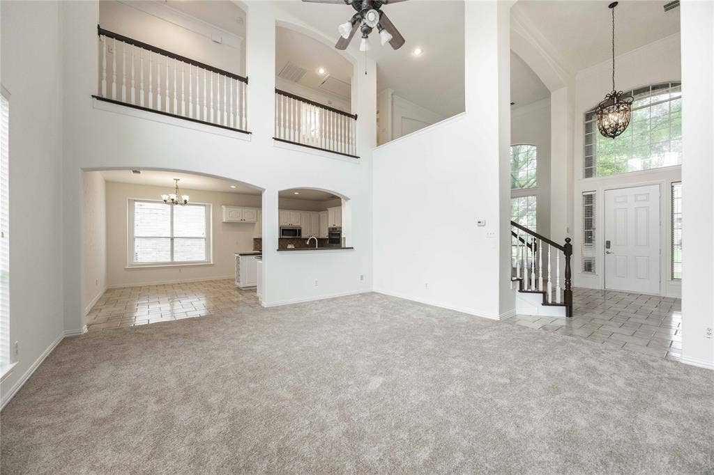3305 Estacado Lane, Plano, TX 75025 Two-story ceiling, arched doorways, white interior paint, wood-finish staircase with white balusters, and a decorative chandelier