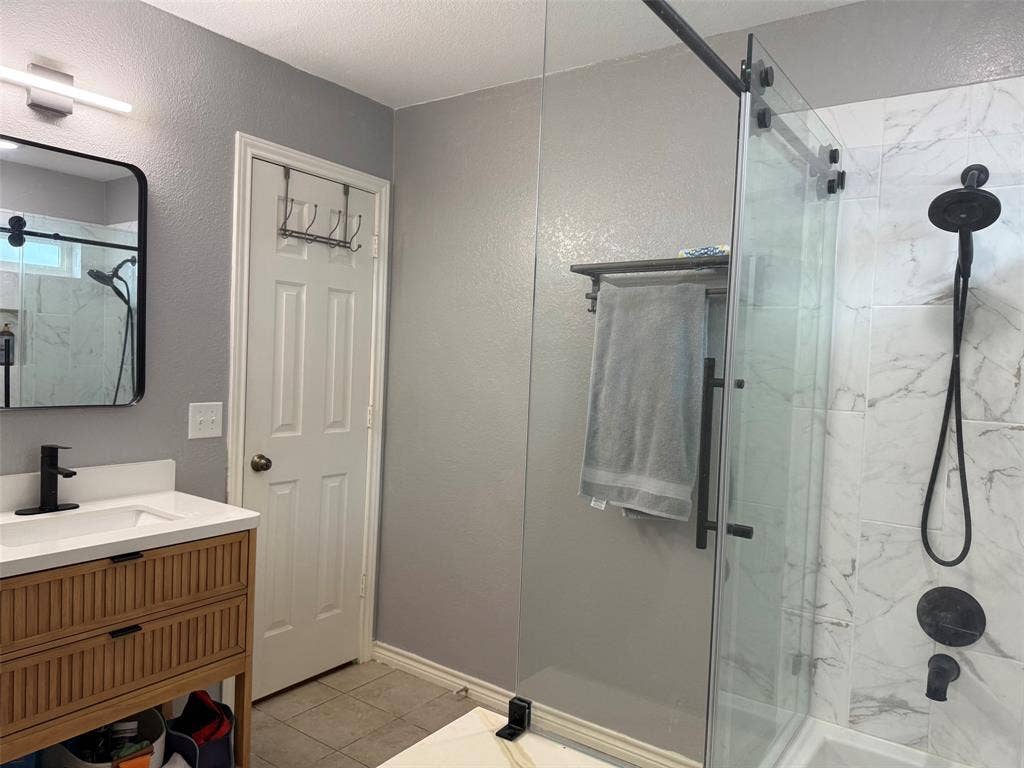 1517 Aylesbury Lane, Plano, TX 75075 Modern bathroom featuring a single vanity with wood-finish fluted cabinetry, white countertop, and black hardware