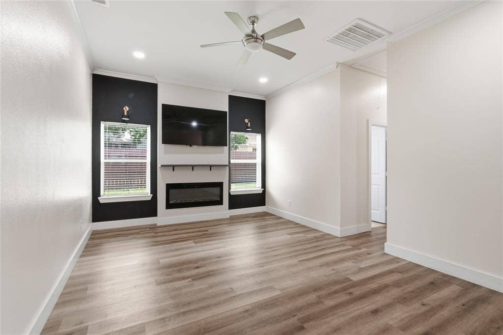 Spacious interior with wood-finish flooring, an integrated electric fireplace, and a ceiling fan