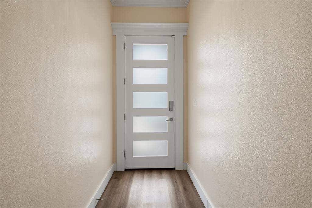 Modern entryway featuring a contemporary front door with frosted glass panels, soaring ceilings, elegant crown molding, and luxury vinyl plank flooring that creates a bright and welcoming first impression