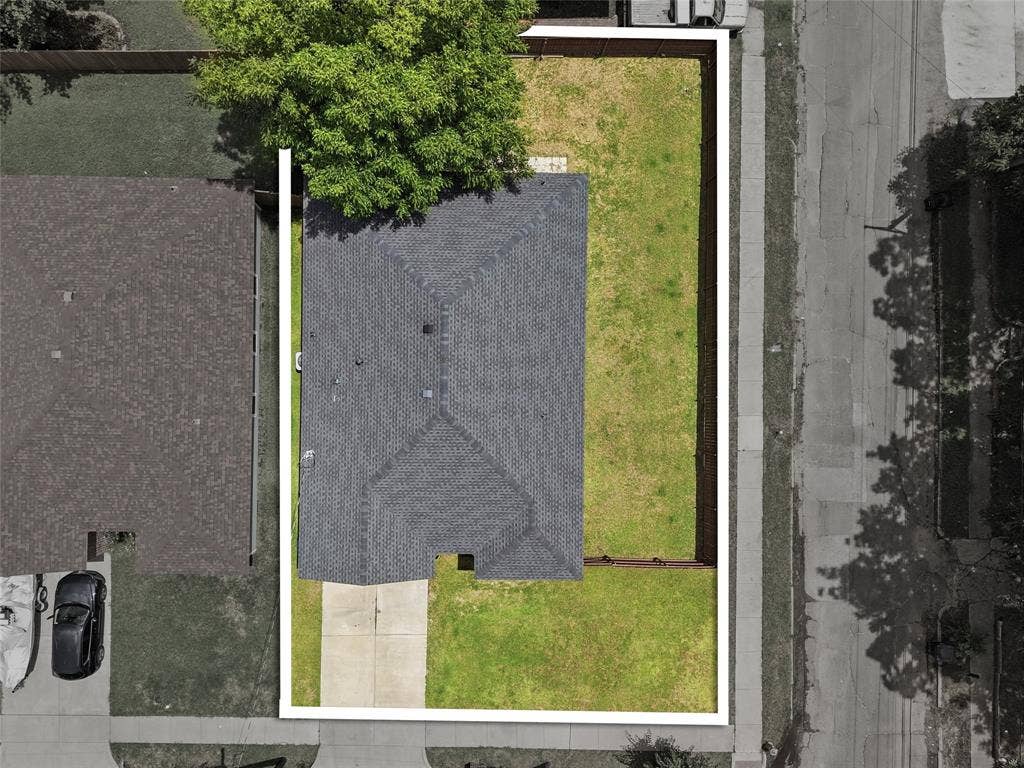 Aerial view showcasing the property's perimeter, a gray shingle roof, a concrete driveway, and a spacious green lawn
