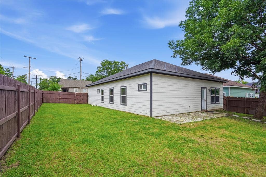 Expansive backyard with a manicured lawn, full privacy fencing, and a concrete patio