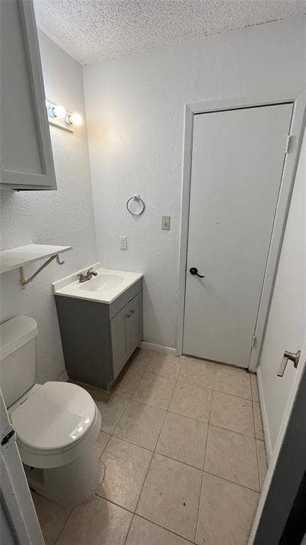Half Bathroom featuring a vanity with an integrated sink, tile flooring, and overhead lighting