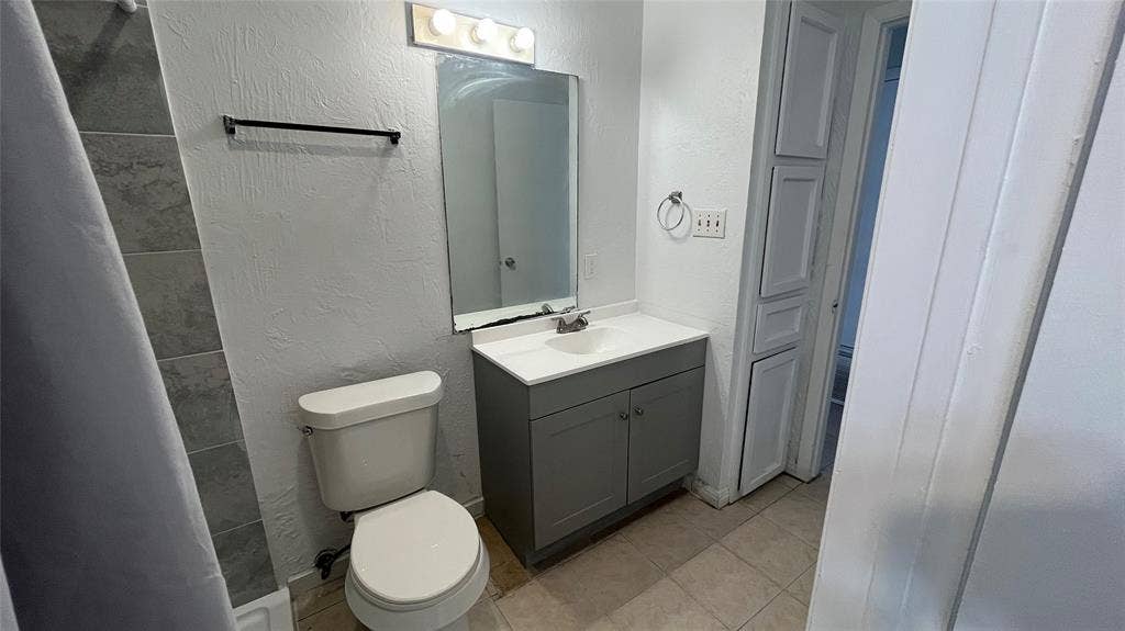 Bathroom 1 featuring a vanity with a white countertop, modern gray cabinetry, a built-in storage cabinet, and tiled flooring