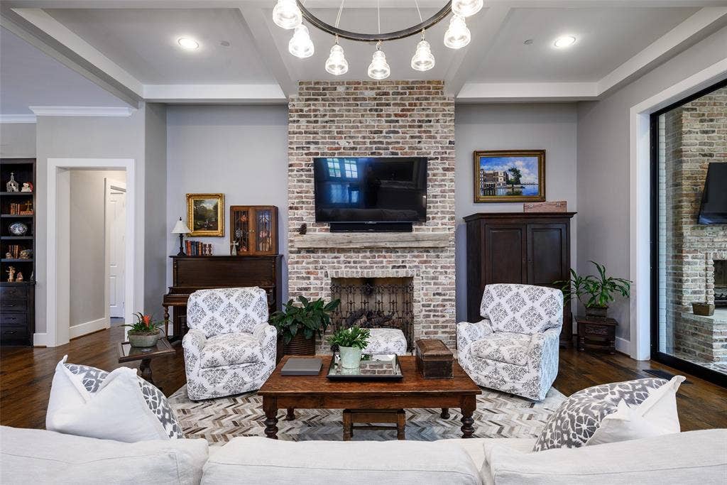 3420 Hanover Street, University Park, TX 75225 Exposed brick fireplace with a wood-mantel, tray ceiling, recessed lighting, and wood-finish flooring