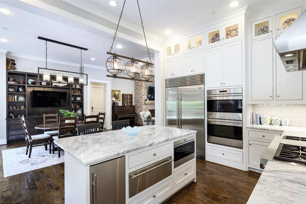 3420 Hanover Street, University Park, TX 75225 Kitchen featuring a substantial island with stone countertop, stainless steel appliances, and extensive white cabinetry