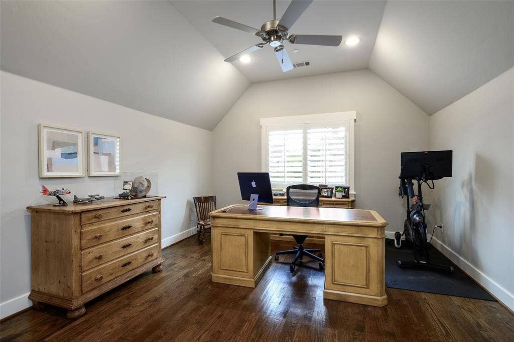 3420 Hanover Street, University Park, TX 75225 Spacious home office featuring vaulted ceilings with ceiling fan and recessed lighting, hardwood flooring, dual wooden desks with ample storage cabinetry, and shuttered windows flooding the room with natural light