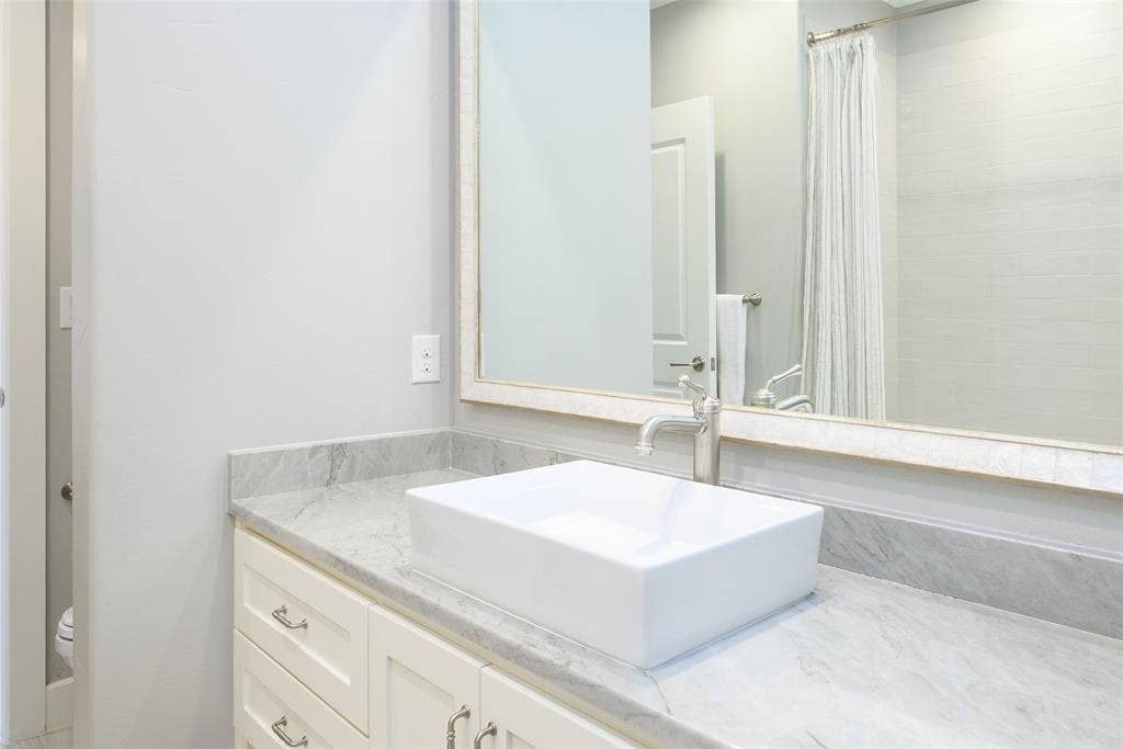 3420 Hanover Street, University Park, TX 75225 Vanity with a rectangular vessel sink, polished chrome faucet, stone countertop, and custom cabinetry