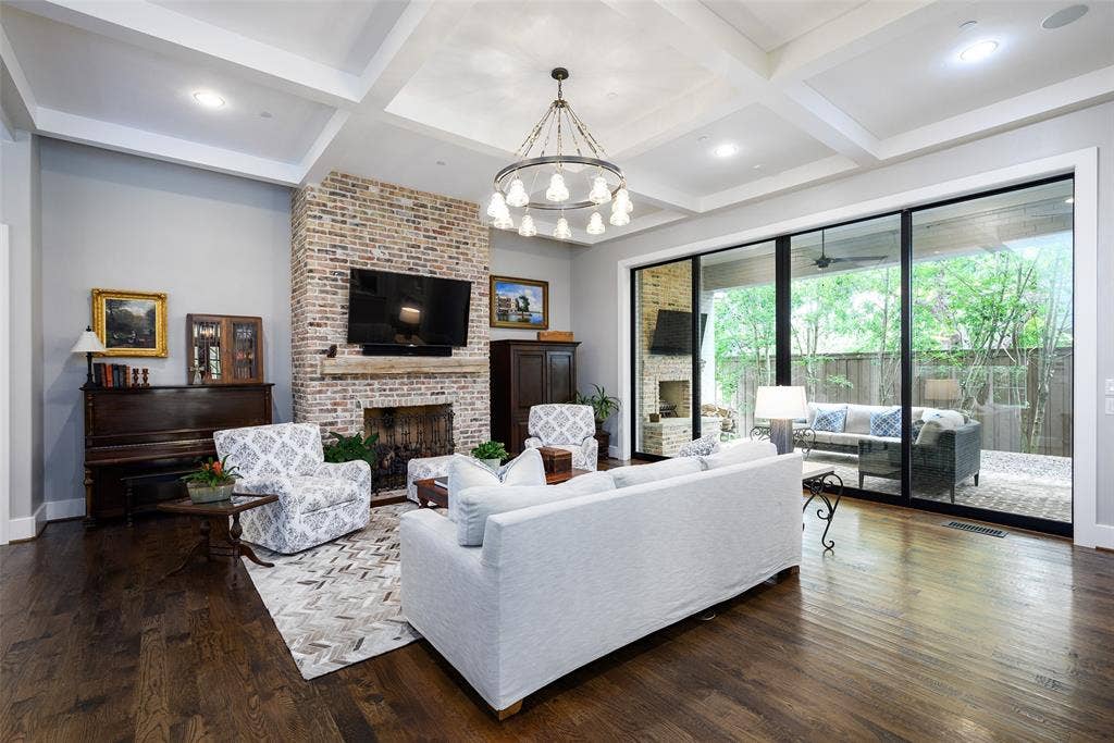 3420 Hanover Street, University Park, TX 75225 Exposed brick fireplace with a wood mantel, coffered ceiling, wood-finish flooring, recessed lighting, and expansive sliding glass doors