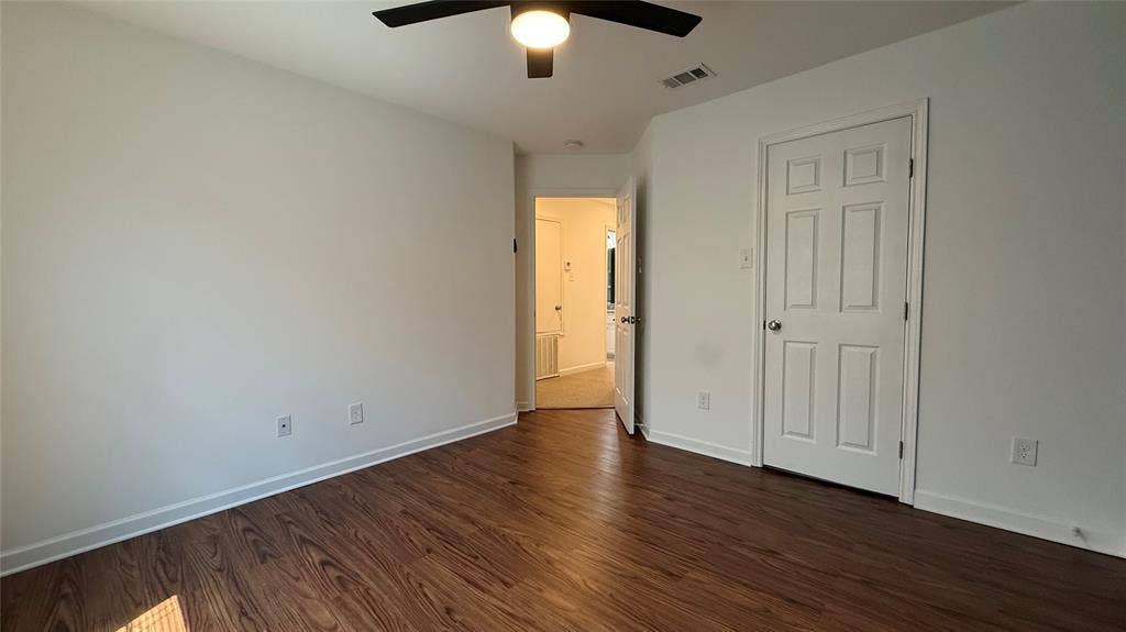 Wood-finish flooring, white paneled door, and a ceiling fan with integrated lighting