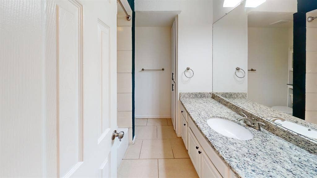 Double vanity with granite-style countertop, dual undermount sinks, and full-width mirror