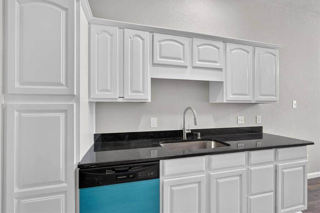 201 West Lane, West Tawakoni, TX 75474 White cabinetry with crown molding, black countertops, stainless steel sink, and a high-arc faucet