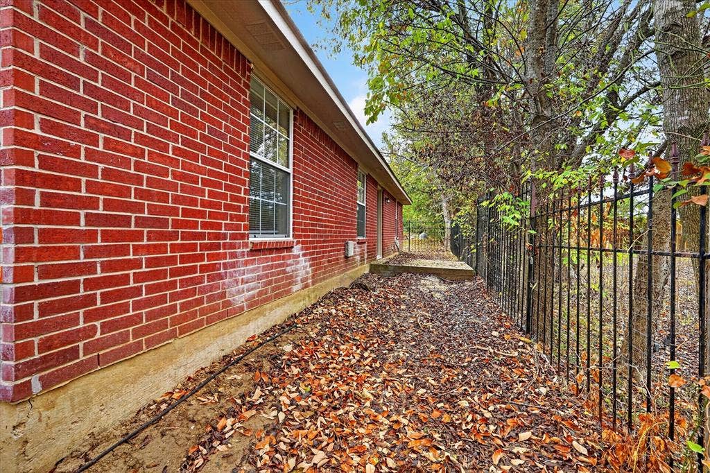 201 West Lane, West Tawakoni, TX 75474 Red brick exterior with white window trim and a black metal fence