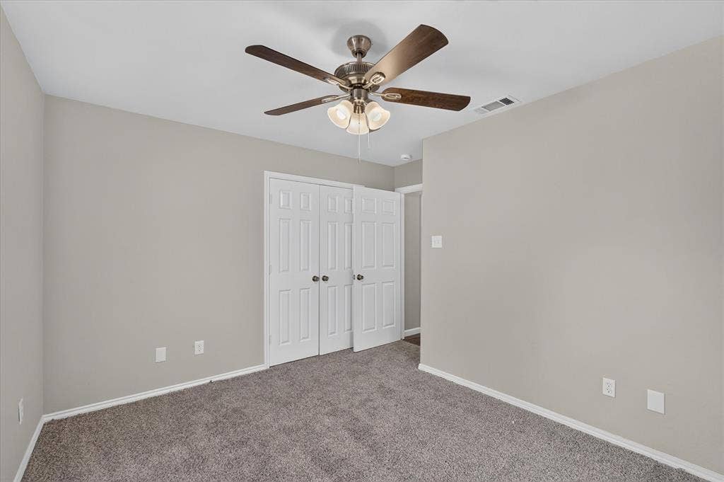 201 West Lane, West Tawakoni, TX 75474 Neutral wall color, carpeted flooring, bi-fold closet doors, and a ceiling fan with integrated lighting