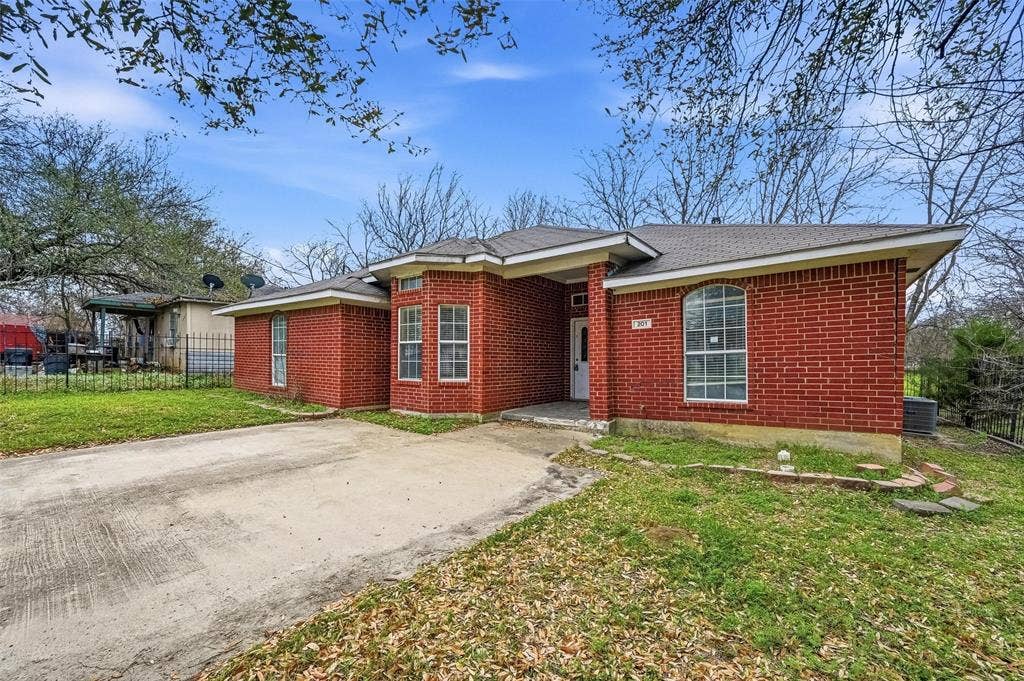 201 West Lane, West Tawakoni, TX 75474 Red brick exterior with a multi-paned bay window, arched window, and a concrete driveway