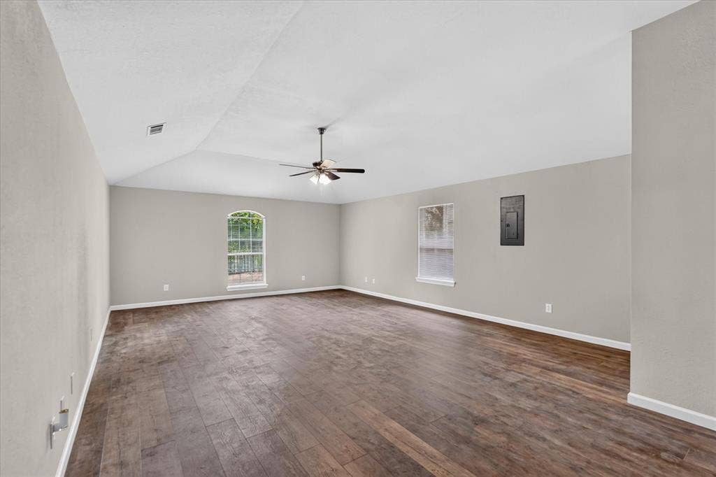 201 West Lane, West Tawakoni, TX 75474 Vaulted ceiling, wood-finish flooring, ceiling fan, arched window, and neutral wall tones