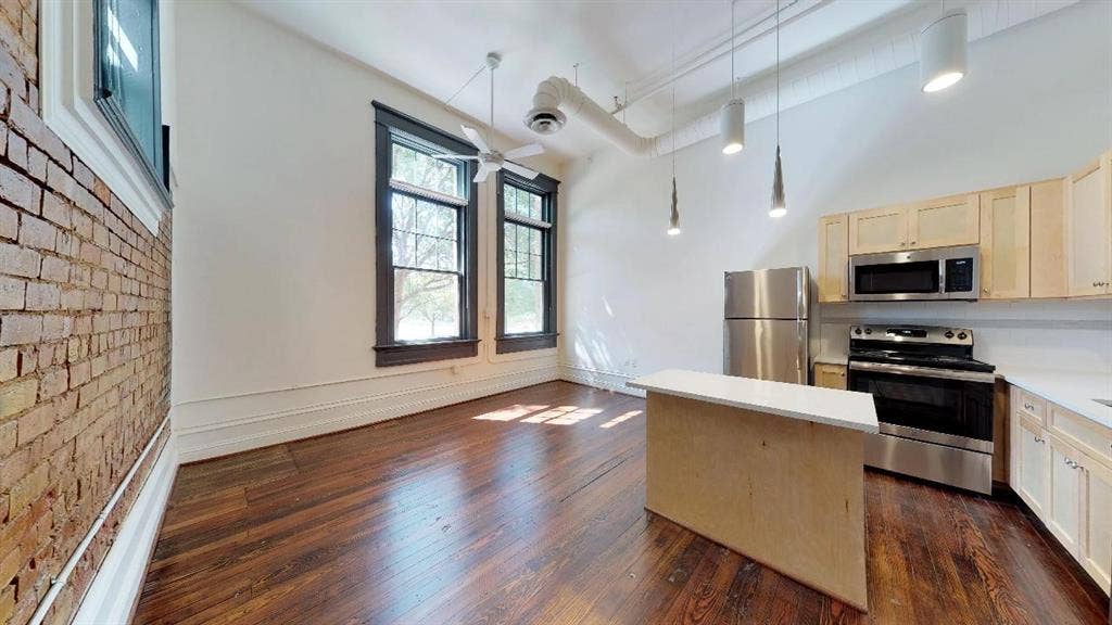 401 N Carroll Avenue, #1116, Dallas, TX 75246 Kitchen featuring decorative light fixtures, dark hardwood / wood-style flooring, brick wall, and appliances with stainless steel finishes