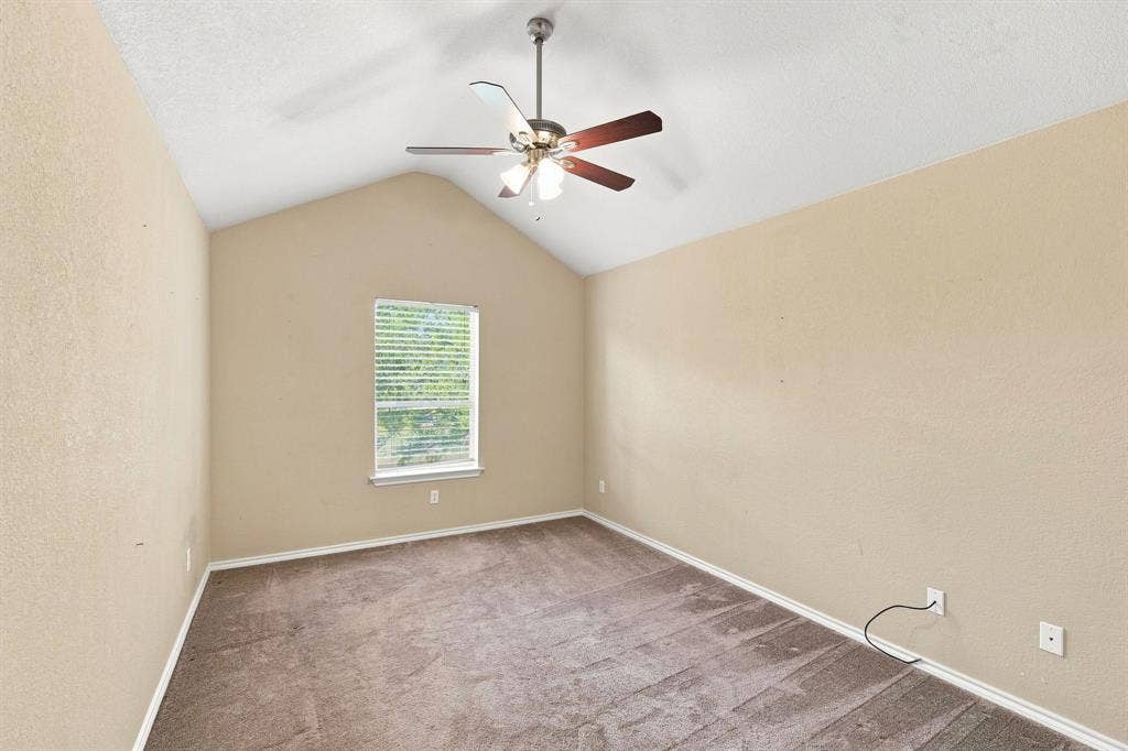 Bright room with a vaulted ceiling, ceiling fan, and calming neutral tones, ready for your personal touch.