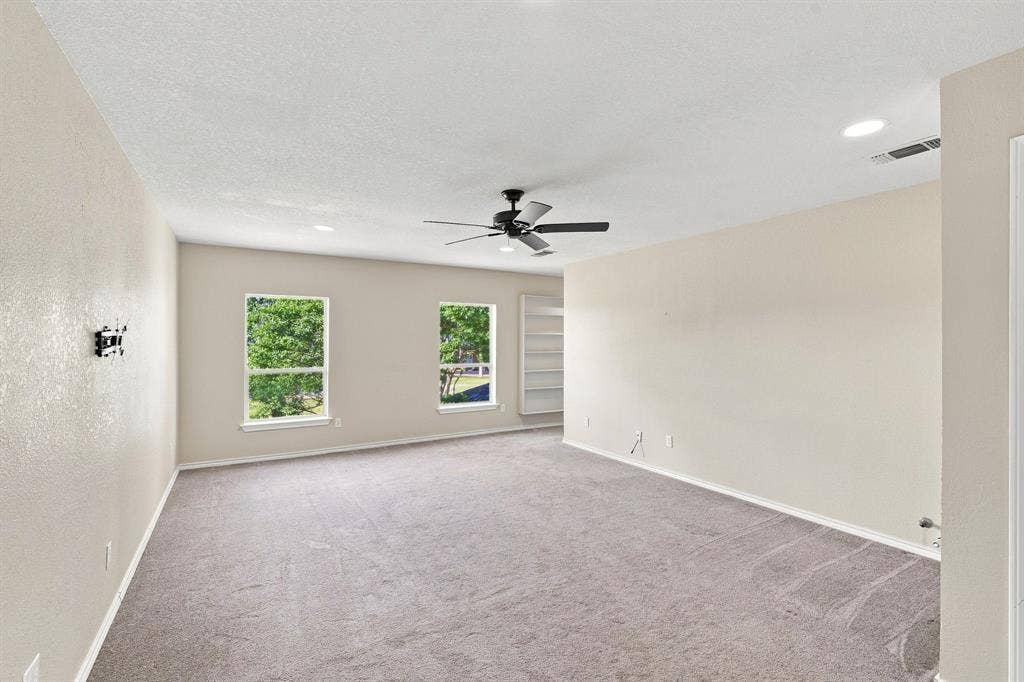 Cozy, light-filled room with recessed lighting, a ceiling fan, two windows, and built-in shelving, flexible space for any lifestyle.