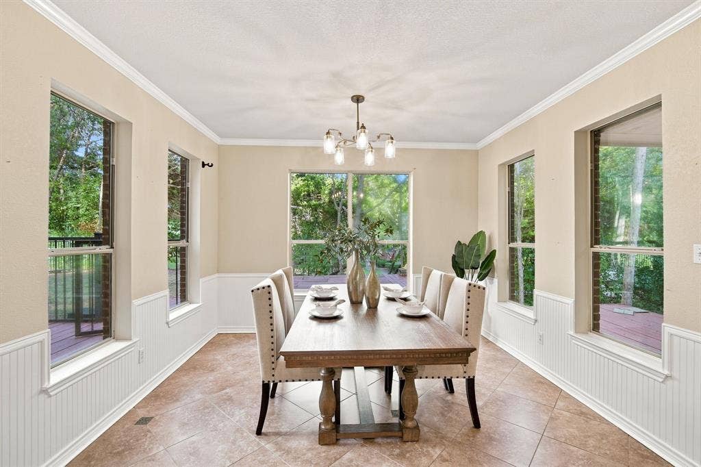 Elegant dining area featuring classic beadboard wainscoting, crown molding, and plenty of natural light from multiple windows.