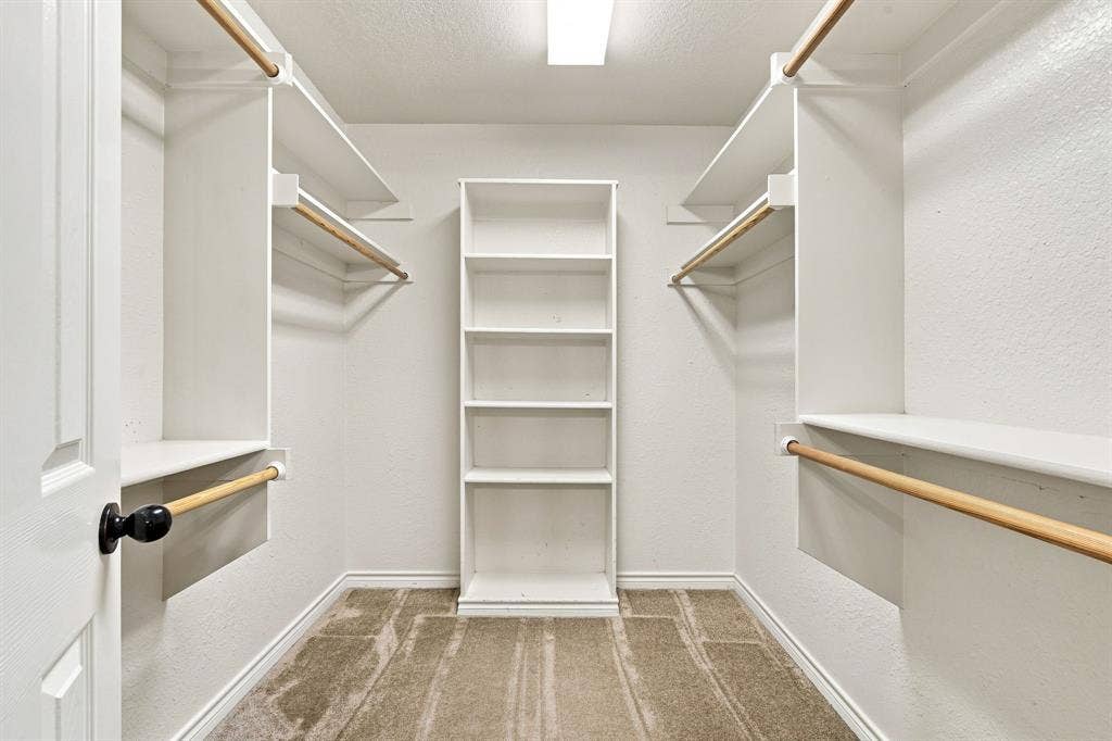 Impressively organized walk-in closet with custom shelving, integrated hanging rods, and built-in central storage.