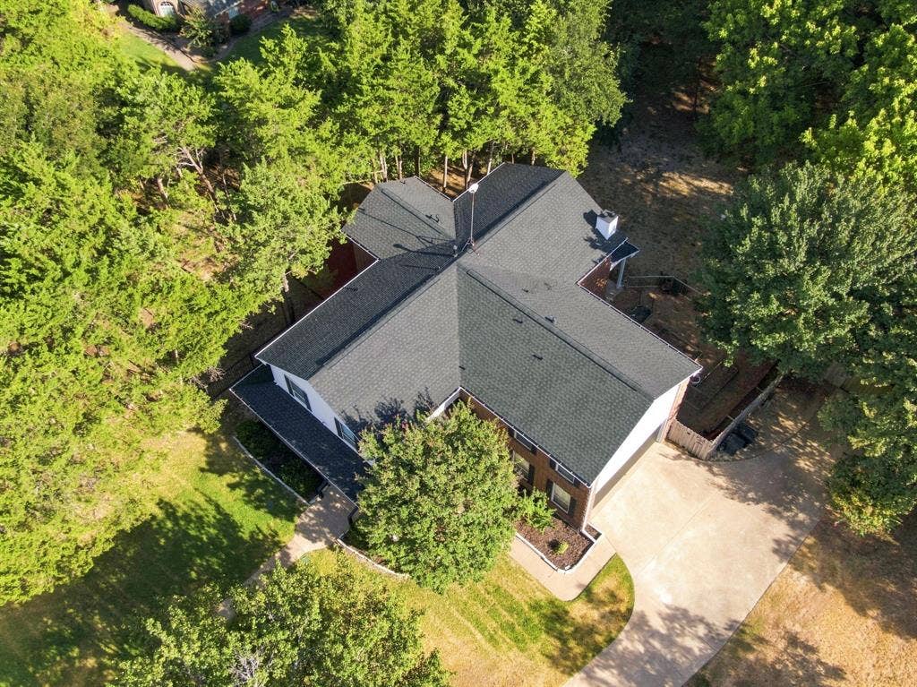Aerial view highlighting the home, surrounded by lush, mature trees.