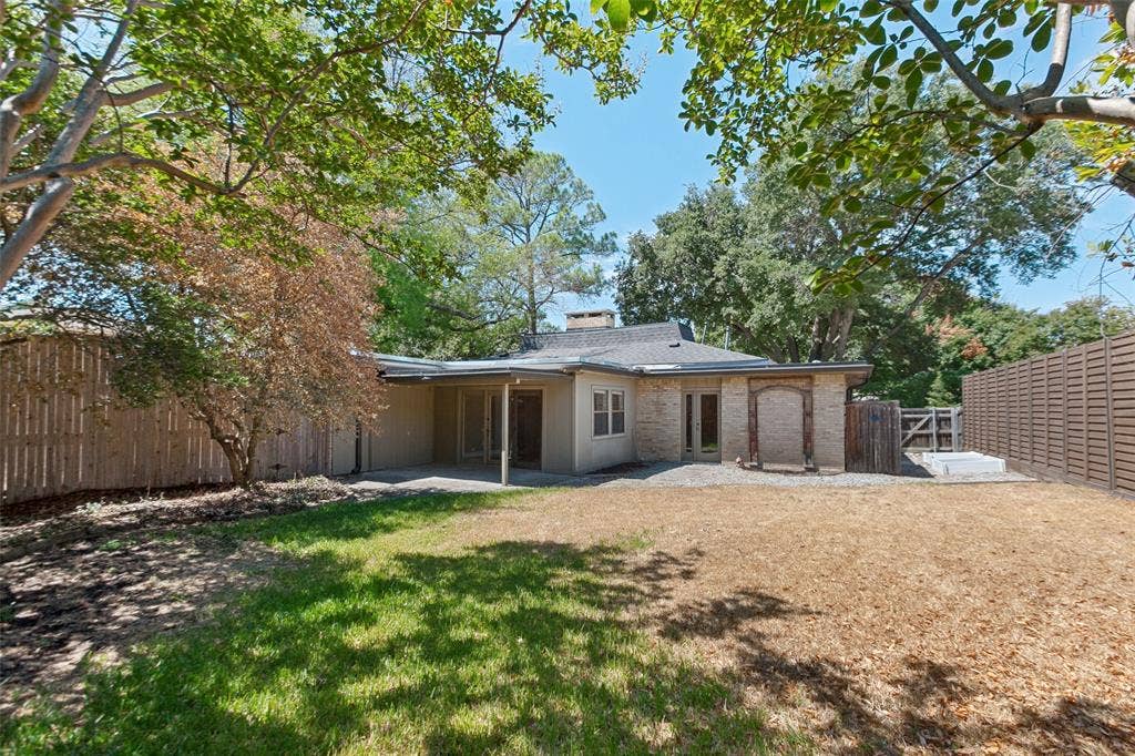 2937 Forest Hills Lane, Richardson, TX 75080 Expansive backyard with a partial grass lawn, mature trees, and a concrete patio