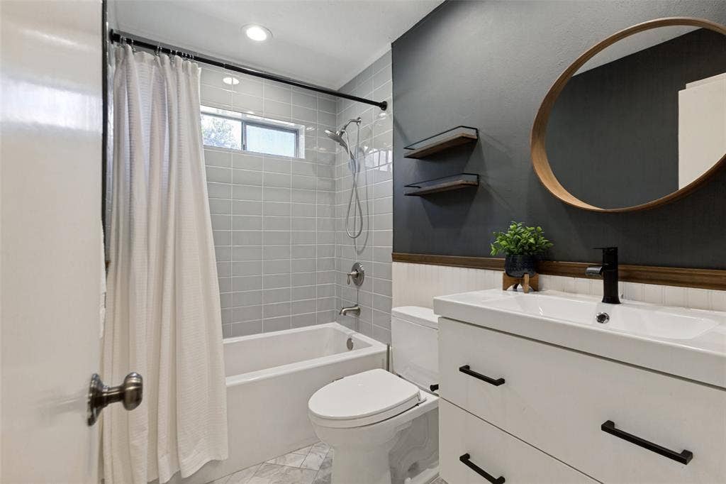 2937 Forest Hills Lane, Richardson, TX 75080 White vanity with matte black hardware, black wall-mounted faucet, and a round wood-frame mirror