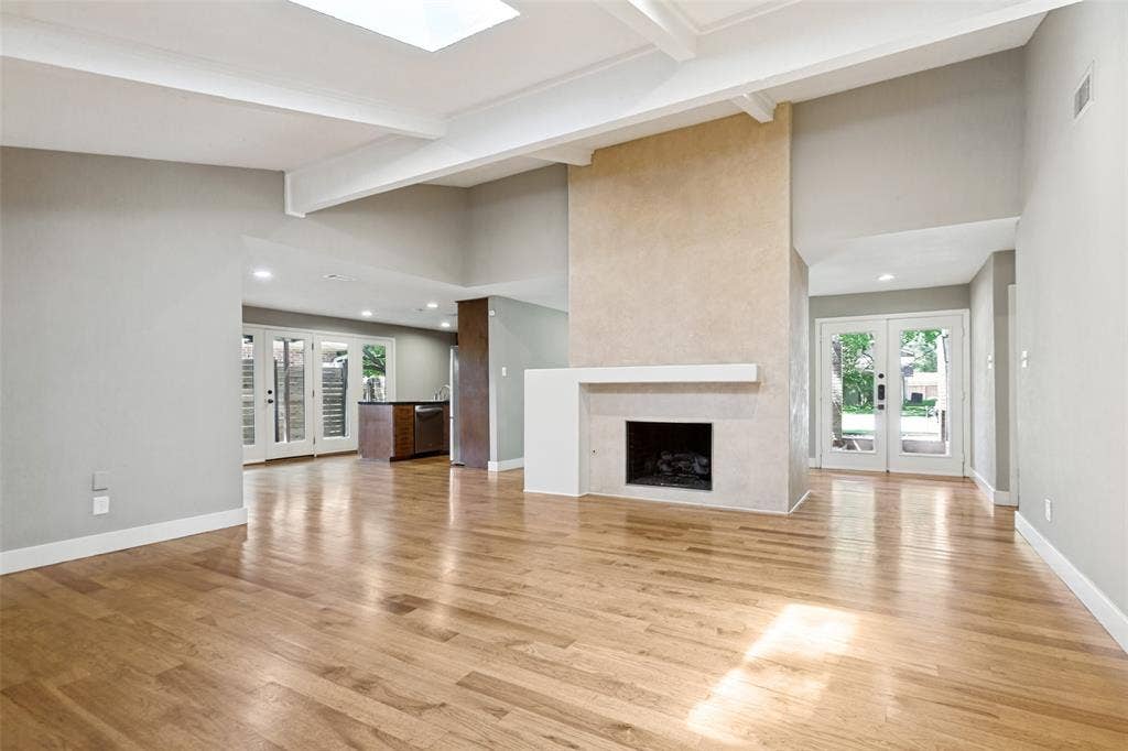 2937 Forest Hills Lane, Richardson, TX 75080 Hardwood flooring, central fireplace with mantle, exposed beam ceiling, recessed lighting, and a skylight