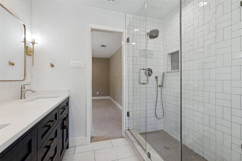 2937 Forest Hills Lane, Richardson, TX 75080 Frameless glass shower enclosure with white subway tile, a built-in shower niche, and a rain shower head