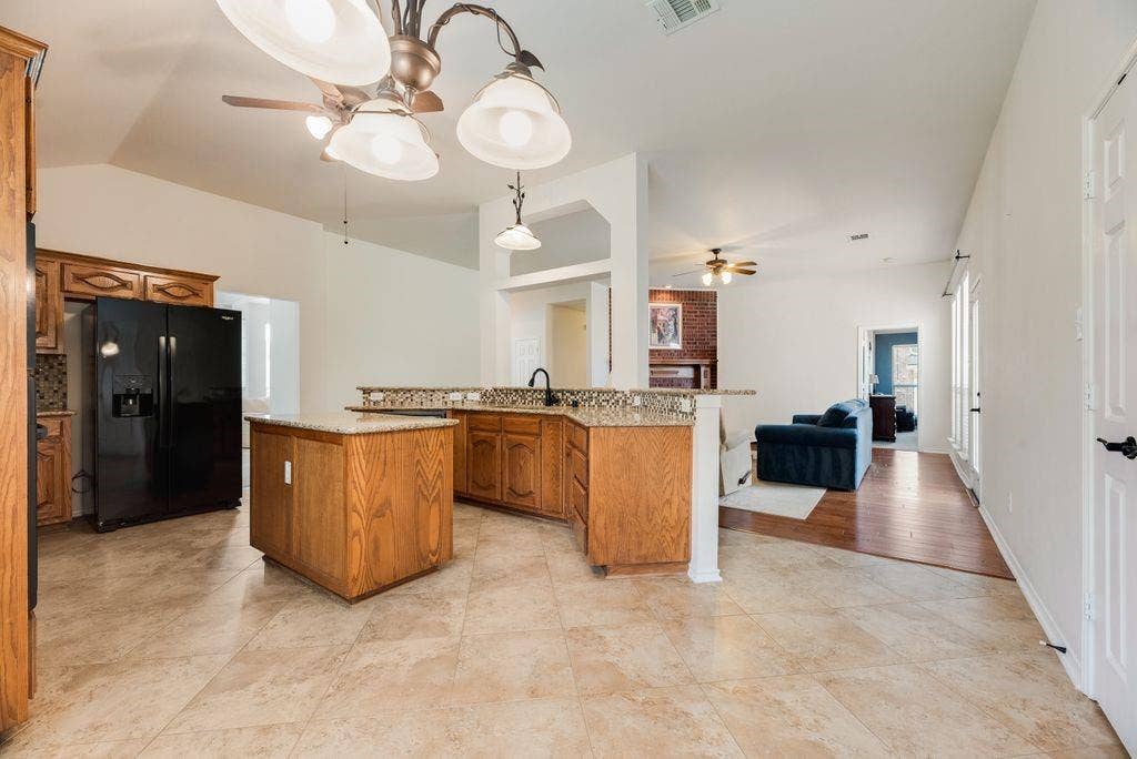 1485 Ashbourne Drive, Rockwall, TX 75087 Kitchen featuring an island, wood cabinetry, granite countertops, and tile flooring