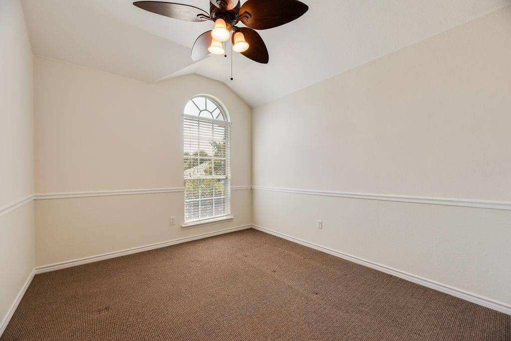 1485 Ashbourne Drive, Rockwall, TX 75087 Bedroom 3, Vaulted ceiling with an attached ceiling fan, arched window with horizontal blinds, and accent wall trim