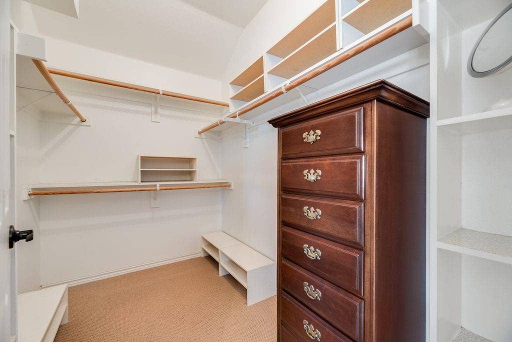 1485 Ashbourne Drive, Rockwall, TX 75087 Primary Closet with Built-in shelving, multiple hanging rods, and an integrated storage bench