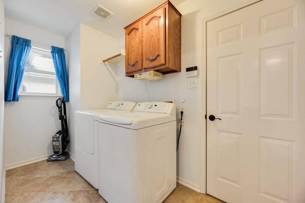 1485 Ashbourne Drive, Rockwall, TX 75087 Laundry area featuring tile flooring, a window, wood cabinetry, and a white paneled door